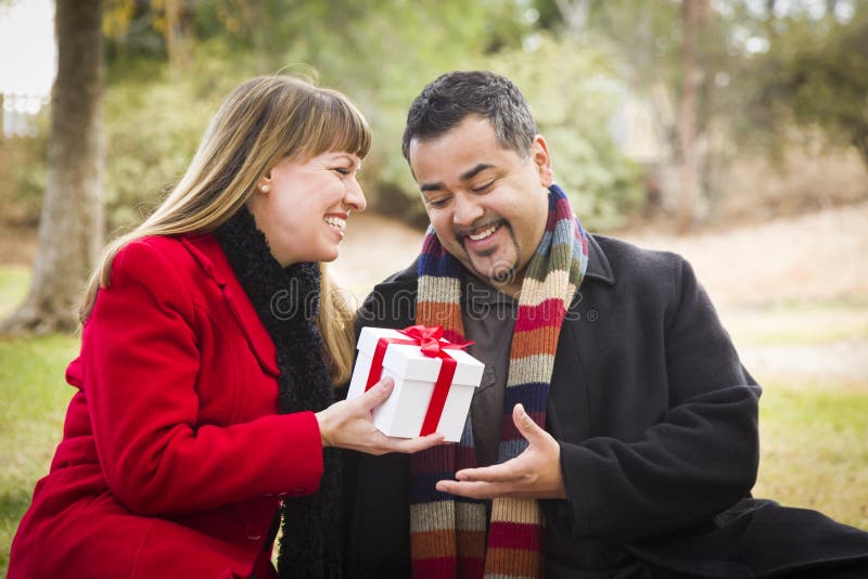 Mixed Race Couple Sharing Christmas or Valentines Day Gift Outdoors