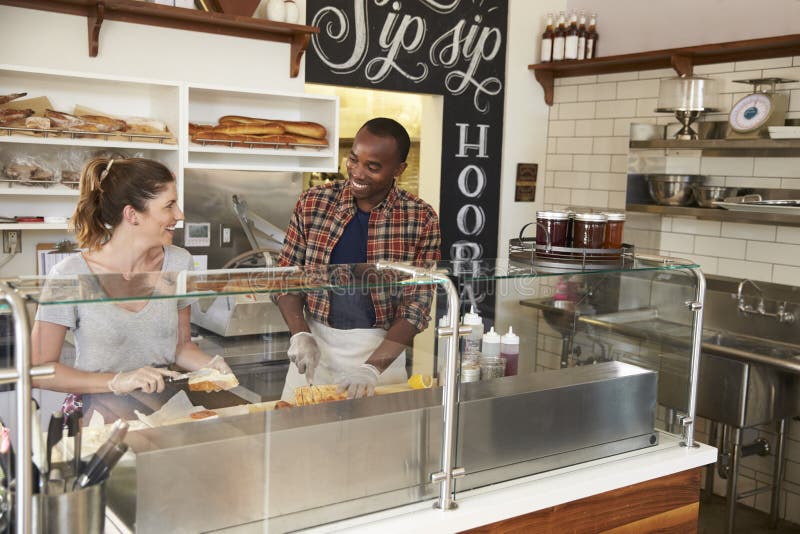 Mixed race couple working behind counter at a sandwich bar stock photos