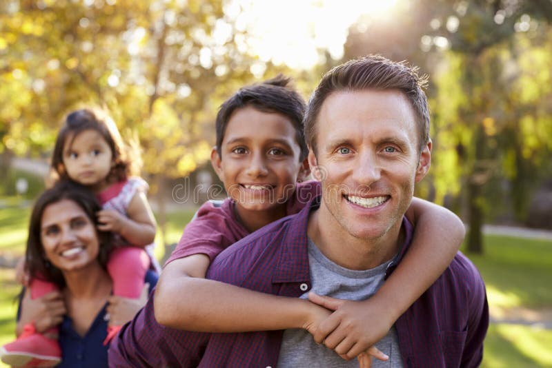 Mixed race parents carry kids piggyback, selective focus
