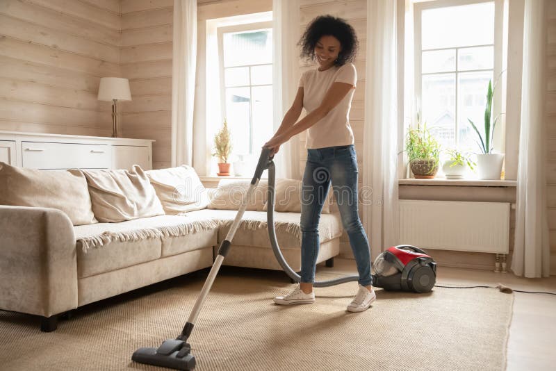 Mixed race woman vacuum cleaning carpet in living room stock images Mixed race woman vacuum cleaning carpet in living room stock images