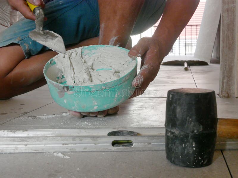 Mixed Tile Grout in a Plastic Bowl in a Construction Worker`s Hands