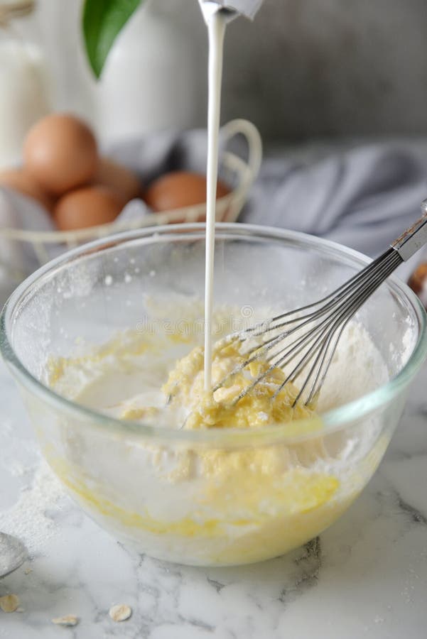 Mixing eggs, flour and milk in bowl. Concept of Cooking ingredients and method on white marble background, Dessert recipes and royalty free stock photography Mixing eggs, flour and milk in bowl. Concept of Cooking ingredients and method on white marble background, Dessert recipes and royalty free stock photography