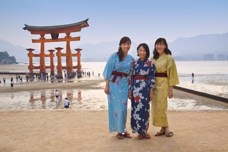 MIYAJIMA, GIAPPONE - 27 MAGGIO: I turisti asiatici davanti al portone di galleggiamento famoso di torii del Itsukushima shrine su fotografia stock MIYAJIMA, GIAPPONE - 27 MAGGIO: I turisti asiatici davanti al portone di galleggiamento famoso di torii del Itsukushima shrine su fotografia stock