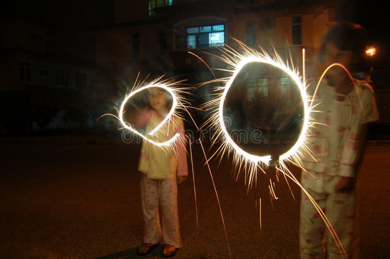 Two kids playing fireworks at night, making circle shape. Two kids playing fireworks at night, making circle shape.