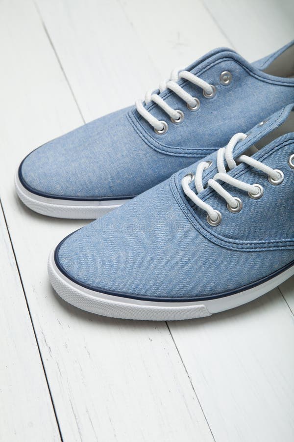 Miękcy wygodni błękitni sneakers na białym drewnianym tle, pionowo zdjęcia royalty free Miękcy wygodni błękitni sneakers na białym drewnianym tle, pionowo zdjęcia royalty free