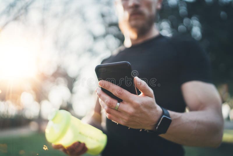 Mięśniowa młoda atleta sprawdza palić kalorie na smartphone zastosowaniu po dobrego treningu plenerowej sesi na pogodnym