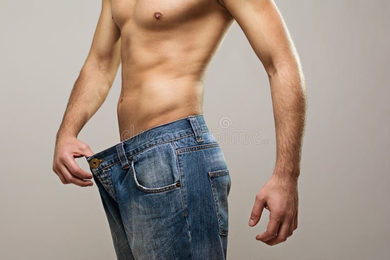 Mięśniowy dysponowany mężczyzna jest ubranym dużych cajgi po diety