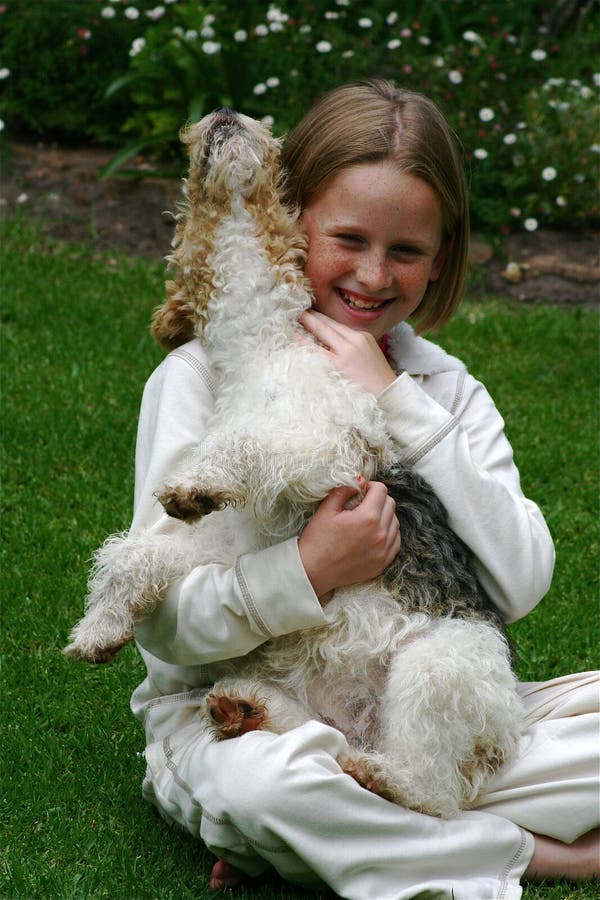 A white caucasian girl child hugging her playful puppy pet in the garden. A white caucasian girl child hugging her playful puppy pet in the garden