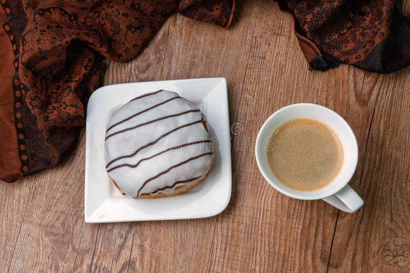 Mjuk åsna med choklad på en vit platta och en kopp kaffe på träbord. Utrymme för översiktskopia royaltyfria bilder