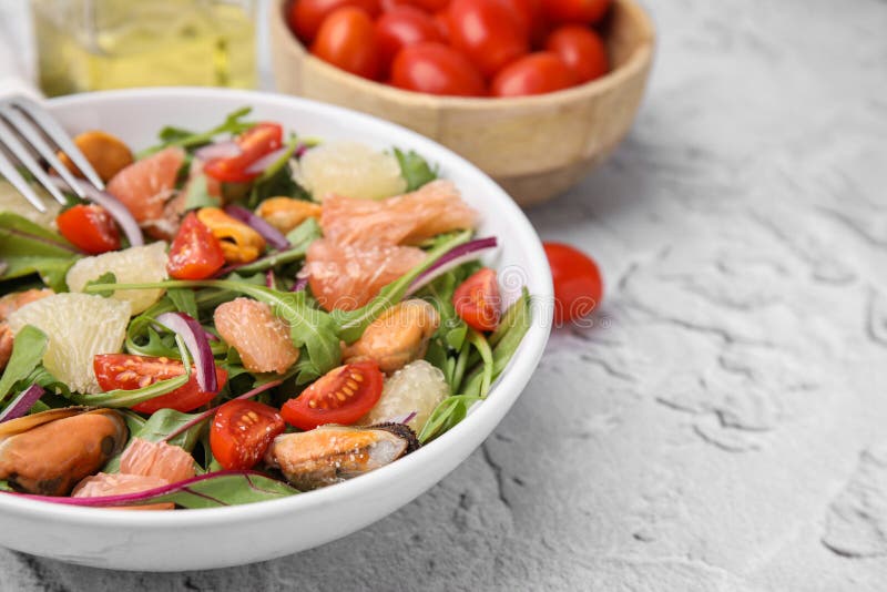 Mjuka pomelosallad med tomater och musslor på vit texturerad bordsduk. utrymme för text arkivfoto