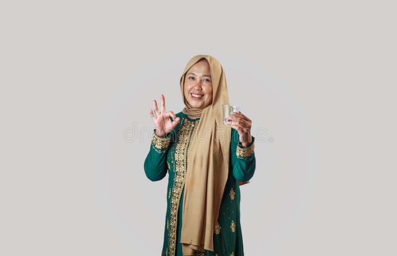 Mjölande kvinnor i traditionell grön press med OK Gesture medan de håller glas royaltyfria foton