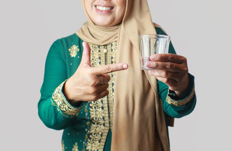Mjölande muslimska kvinnor i traditionell utsmyckning i glas vatten royaltyfria bilder
