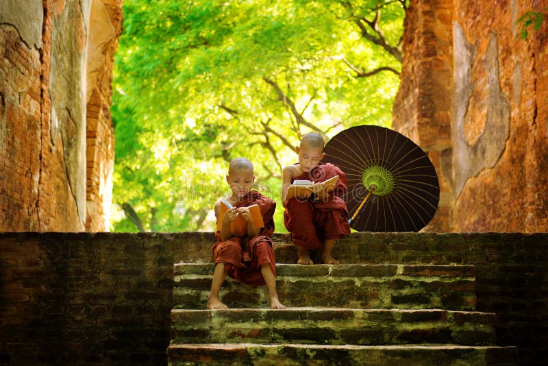 Young Buddhist monk reading outdoors, sitting outside monastery, Myanmar. Young Buddhist monk reading outdoors, sitting outside monastery, Myanmar.