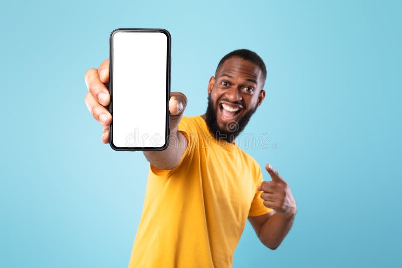 Mobile app advertisement. Excited black man pointing at smartphone with empty screen, mockup. Space for ad or website