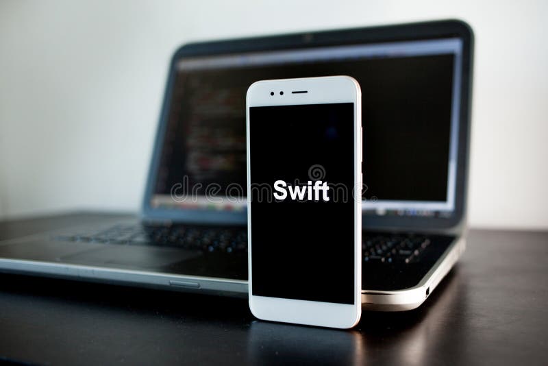 Mobile application development, Swift programming language for mobile development. Workplace of programmer, tester, laptop, and smartphone
