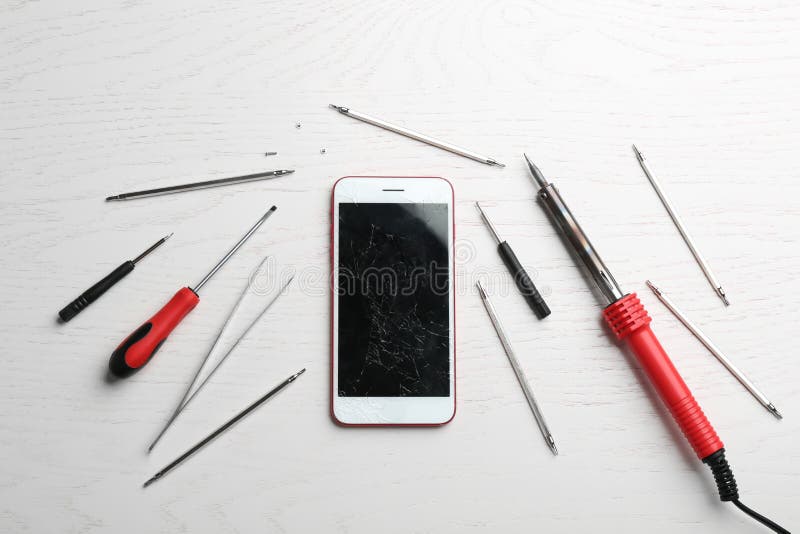 Mobile Phone with Broken Display and Repair Tools on Wooden Table Stock