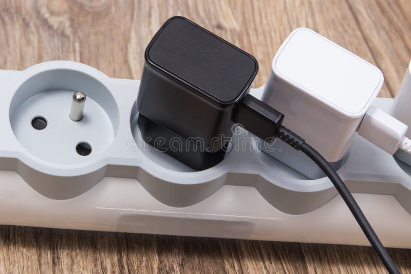 Mobile phone chargers connected to electrical power strip. Various devices charging royalty free stock image