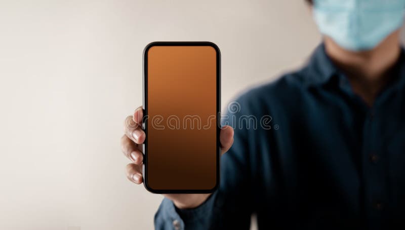 Mobile Phone Mockup Image. Display Screen is Blank. Person with a Surgical Mask on Face Holding a Smartphone towards the Camera stock photography