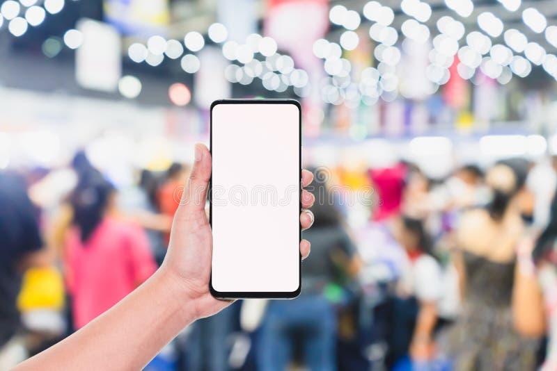 Mobile phone mockup image, hand holding blank screen mobile smart phone with blurred Crowd of people in the shopping store royalty free stock photos.