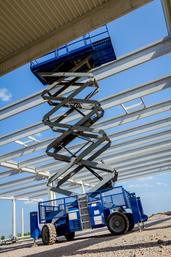 Mobile scaffold, stretched scissor lift platform at construction. Scissor lift platform with stretched hydraulic system at maximum height range under building royalty free stock photography Mobile scaffold, stretched scissor lift platform at construction. Scissor lift platform with stretched hydraulic system at maximum height range under building royalty free stock photography