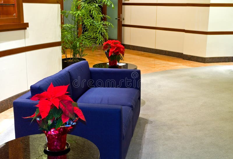 Blue couch in a modern office building lobby with red poinsettias on two end tables. Blue couch in a modern office building lobby with red poinsettias on two end tables.