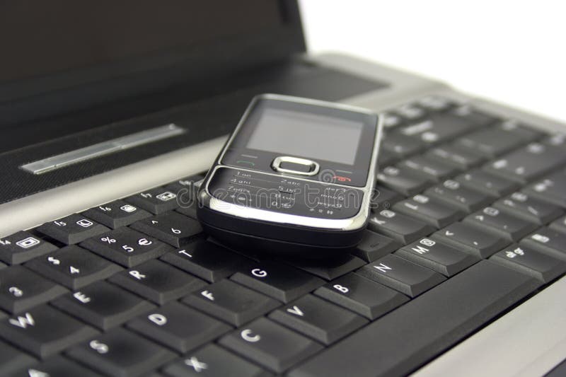 Mobiltelefon auf einem Notizbuchtastaturblock stockbild Mobiltelefon auf einem Notizbuchtastaturblock stockbild