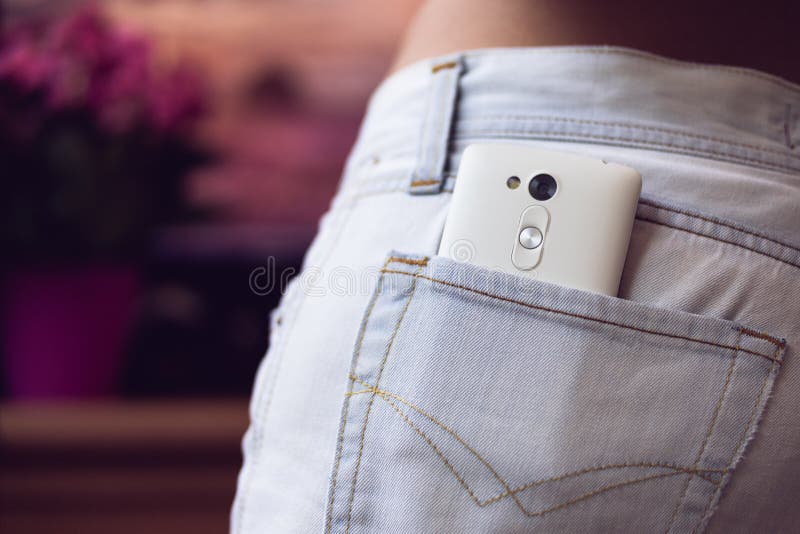 Mobiltelefon i bakfickakvinnornas jeans på en purpurfärgad backgr royaltyfri foto Mobiltelefon i bakfickakvinnornas jeans på en purpurfärgad backgr royaltyfri foto