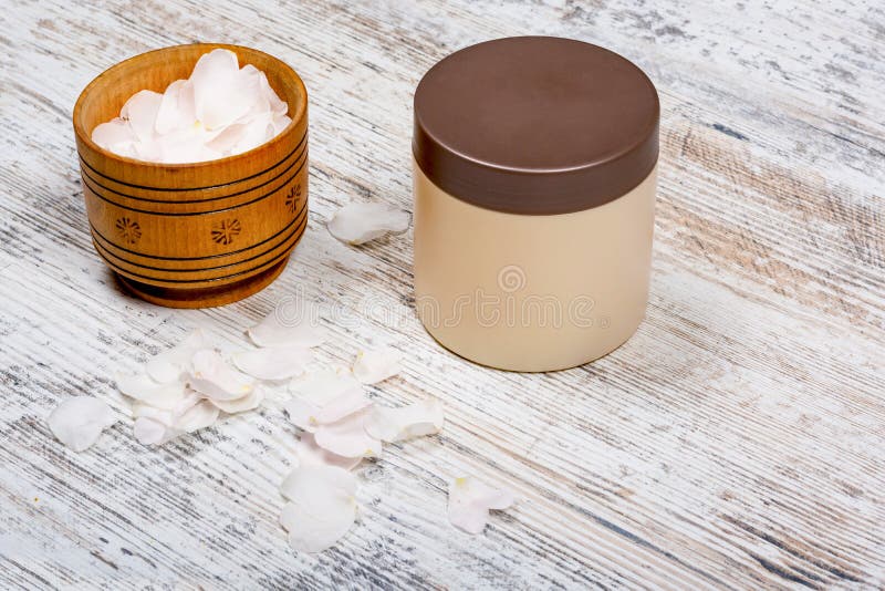 Mocap beige de banque pour de la cuvette crème et en bois de pétales de rose se tenant sur un fond texturisé en bois minable photographie stock libre de droits Mocap beige de banque pour de la cuvette crème et en bois de pétales de rose se tenant sur un fond texturisé en bois minable photographie stock libre de droits