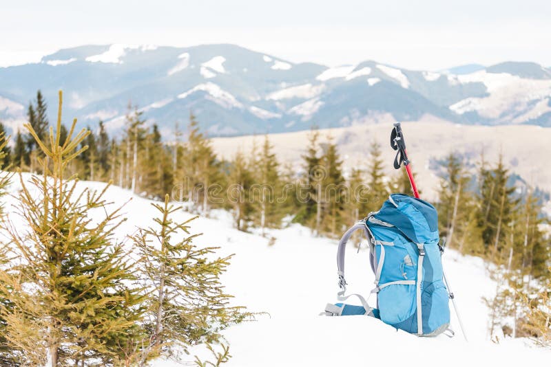 Haga excursionismo en el fondo de montañas coronadas de nieve y del cielo azul Una mochila en la nieve Forma de vida activa El emigrar en invierno Equipo para caminar Palillos del senderismo