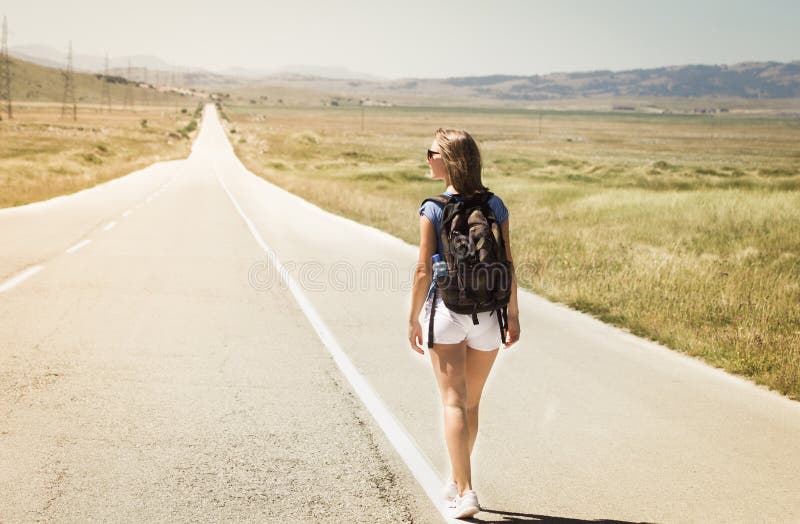 Mochileiro da mulher que anda na estrada foto de stock Mochileiro da mulher que anda na estrada foto de stock
