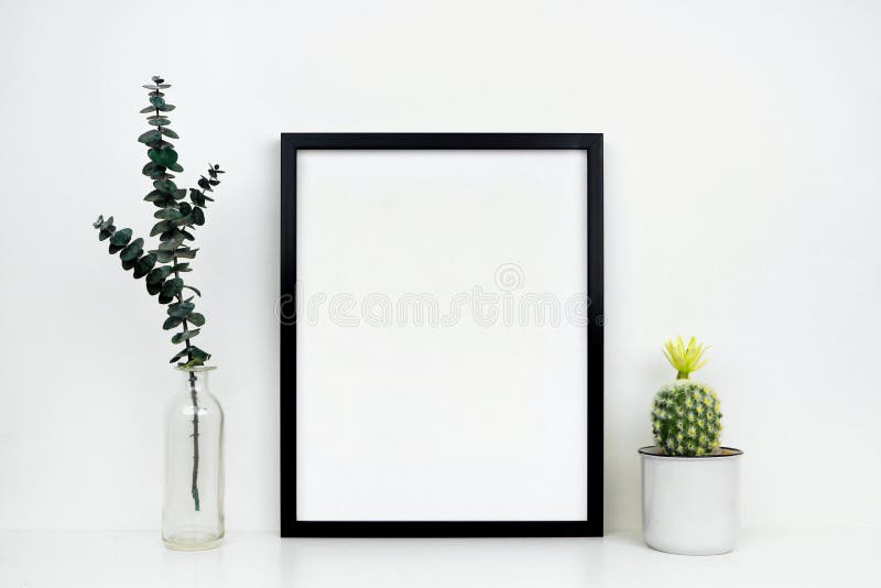 Mock up black frame with cactus and branches on a white shelf or desk against a white wall royalty free stock images Mock up black frame with cactus and branches on a white shelf or desk against a white wall royalty free stock images