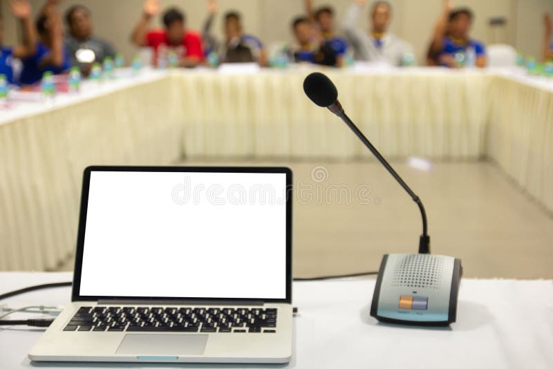 Mock up laptop computer with blank screen on table in meeting room with blur people in background. stock images