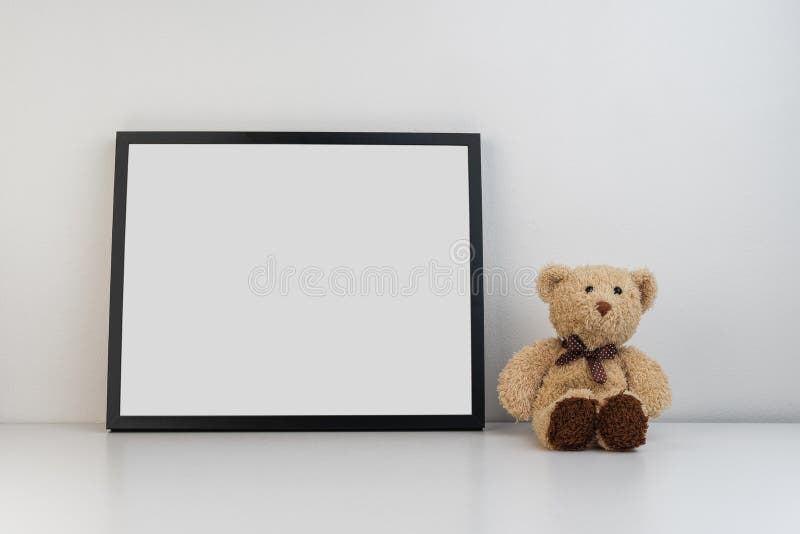 Mock up photo frame on table with a teddy bear as decoration