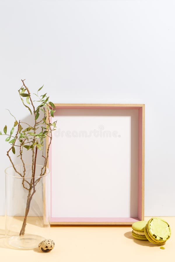 Mock up white frame and branch with green leaves in blue vase on book shelf or desk. Minimalistic concept royalty free stock photos Mock up white frame and branch with green leaves in blue vase on book shelf or desk. Minimalistic concept royalty free stock photos