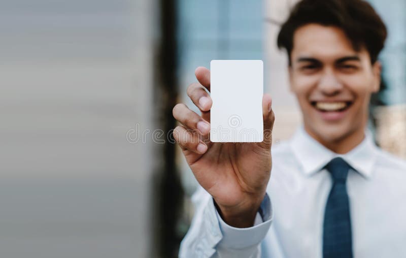 Mockup-bild för visitkort Glad ung affärsman som presenterar ett vitt, tomt papperskort arkivbild