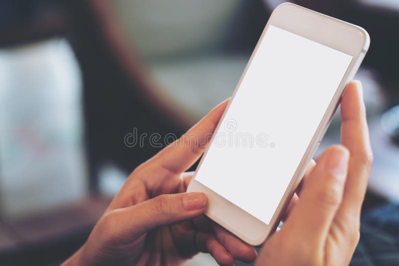 Hand holding mobile phone with blank white screen in vintage cafe