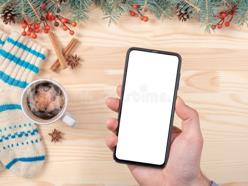 Mockup image of a man`s hand holding black mobile phone with blank screen on christmas background. Smartphone in hand for stock image