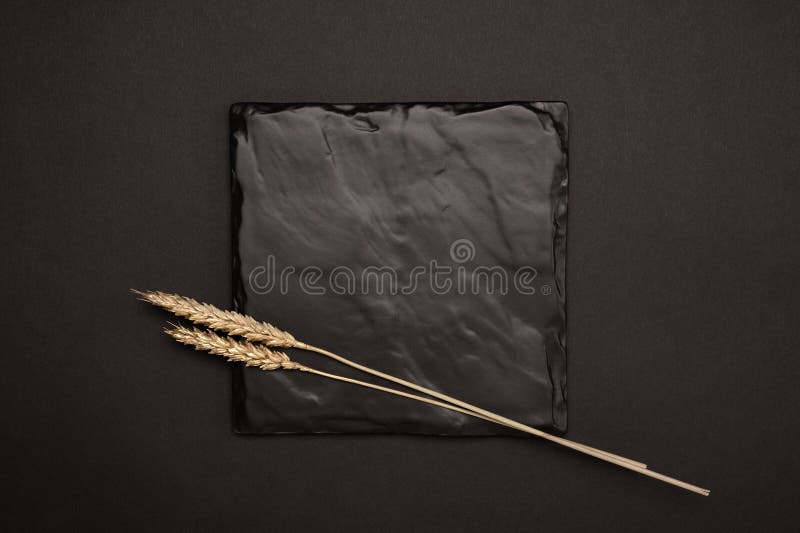 Mockup image. Square black stone plaque plate mock up with a gold wheats. Top view of a black card mockup with golden wheats royalty free stock photo