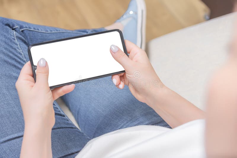 Mockup image of woman`s hands holding white mobile phone with blank screen in horizontal position royalty free stock photography