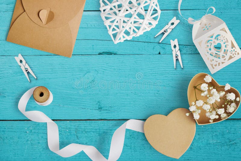 Mockup Letter with paper hearts, kraft box with flowers for greeting card St. Valentine`s Day in rustic style with place for your text on a turquoise wooden background. Flat lay, top view mock up.