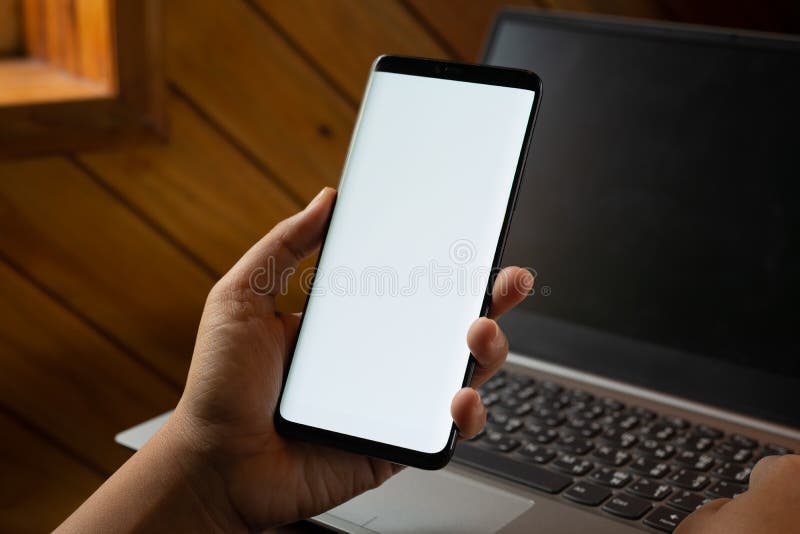 Mockup mobile phone image. Close up hands using modern smart phone Technology with blurred laptop background. Mobile phone with royalty free stock image