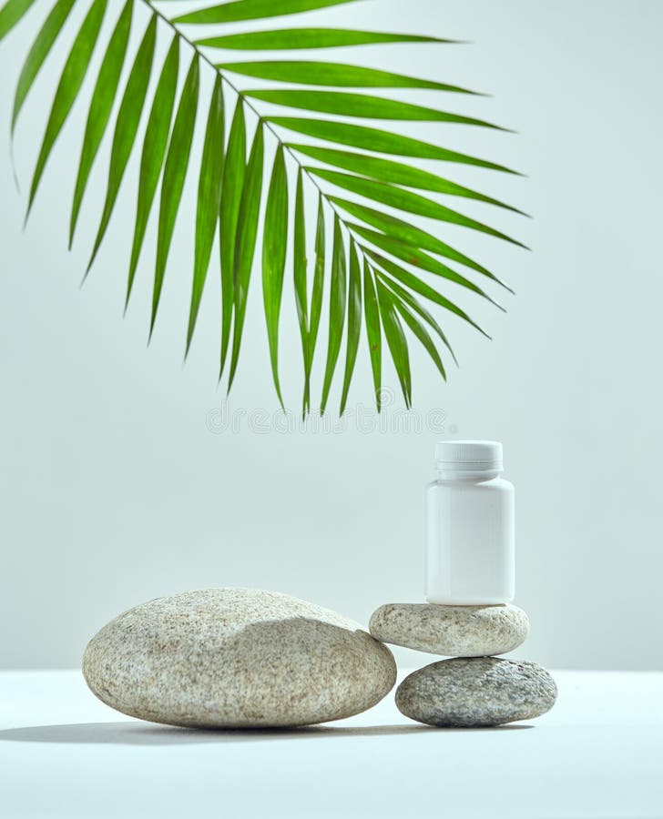 Mockup white plastic jar on natural stones podium, green palm leaf. Presentation of dietary supplements, vitamins. Template bottle for product design. Copy space. High quality photo