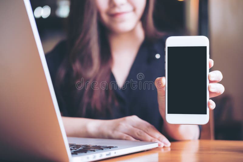 Mockup wizerunek smiley Azjatycka piękna kobieta trzyma białego telefon komórkowego z pustym czerń ekranem i pokazuje podczas gdy zdjęcia royalty free