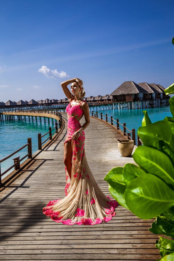 Mode De Luxe. Mannequin Élégant. Modèle Féminin Élégant En Robe Longue  Rouge Sur La Plage Des Maldives. Élégance. Femme Chic En Robe Rouge  Incroyable Près De La Piscine. Couture. Vogue. Banque D'Images