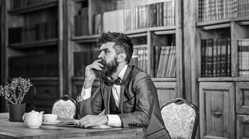 Moda del viejo estilo y del varón El hombre barbudo se sienta en biblioteca con el libro viejo El hombre maduro en traje elegante foto de archivo libre de regalías Moda del viejo estilo y del varón El hombre barbudo se sienta en biblioteca con el libro viejo El hombre maduro en traje elegante foto de archivo libre de regalías