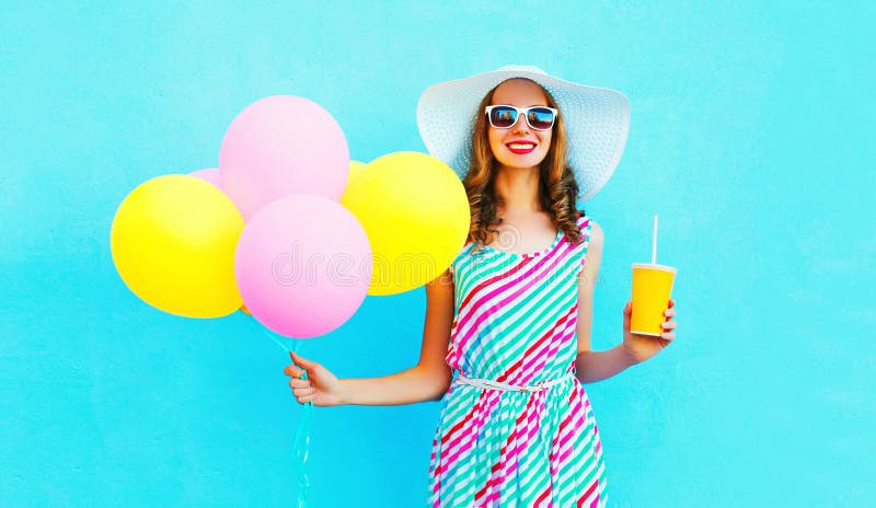 Moda dosyć uśmiecha się kobiety trzyma owocowego soku filiżankę z lotniczy kolorowi balony zdjęcia stock Moda dosyć uśmiecha się kobiety trzyma owocowego soku filiżankę z lotniczy kolorowi balony zdjęcia stock