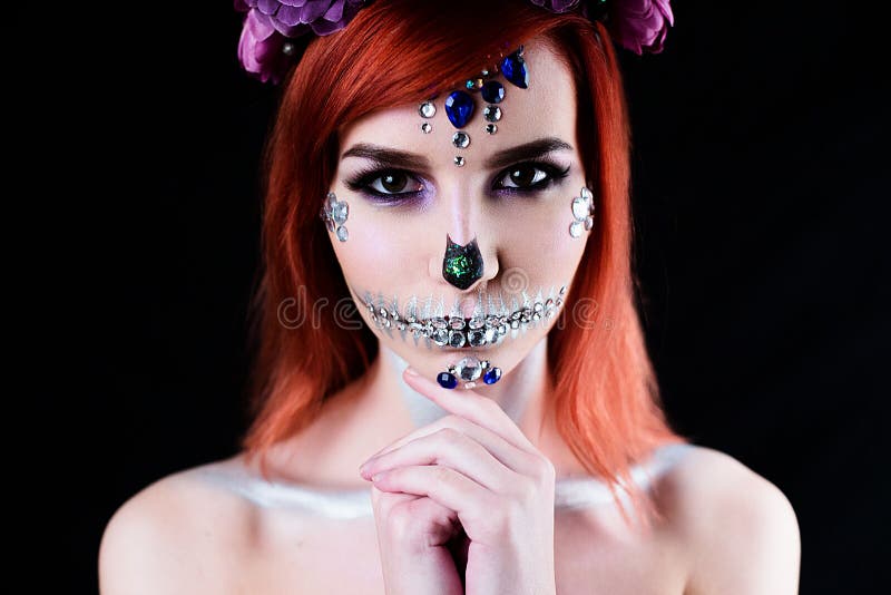 Fashion model with halloween skull makeup with glitter and rhinestones on black studio background. Fashion model with halloween skull makeup with glitter and rhinestones on black studio background