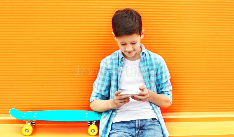 Moda nastolatka chłopiec używa smartphone, deskorolka na kolorowym obrazy royalty free Moda nastolatka chłopiec używa smartphone, deskorolka na kolorowym obrazy royalty free