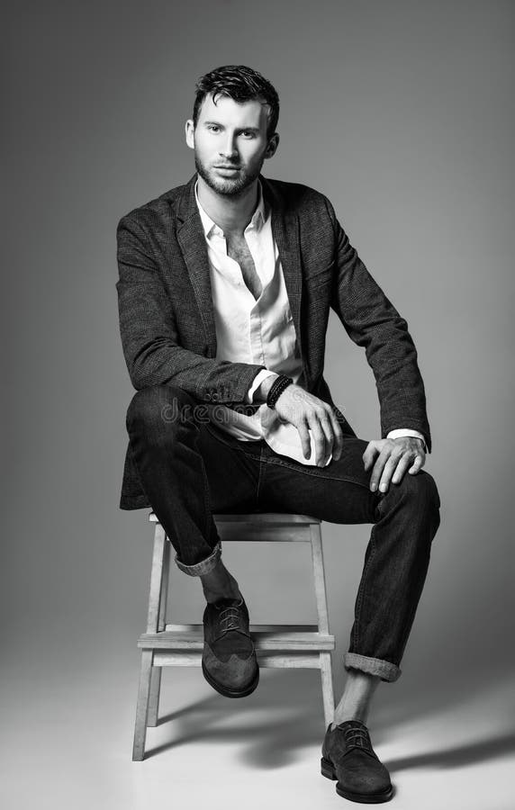 Mode de studio tirée : portrait de jeune homme beau dans les jeans, la chemise et la veste se reposant sur le banc Rebecca 36 photographie stock libre de droits Mode de studio tirée : portrait de jeune homme beau dans les jeans, la chemise et la veste se reposant sur le banc Rebecca 36 photographie stock libre de droits