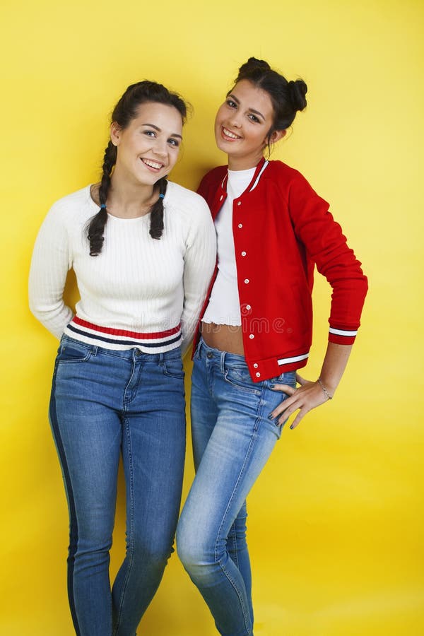 Mode de vie : deux jolies jeunes filles de l'école s'amusant heureux sourire sur fond jaune photos libres de droits